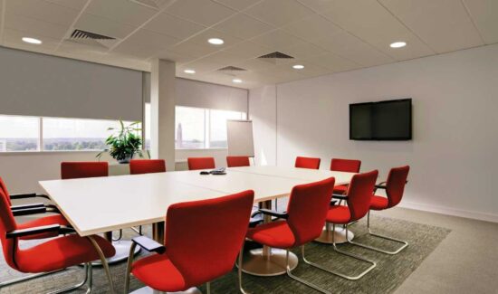 Moderner Konferenzraum mit roten Stühlen und großem Tisch