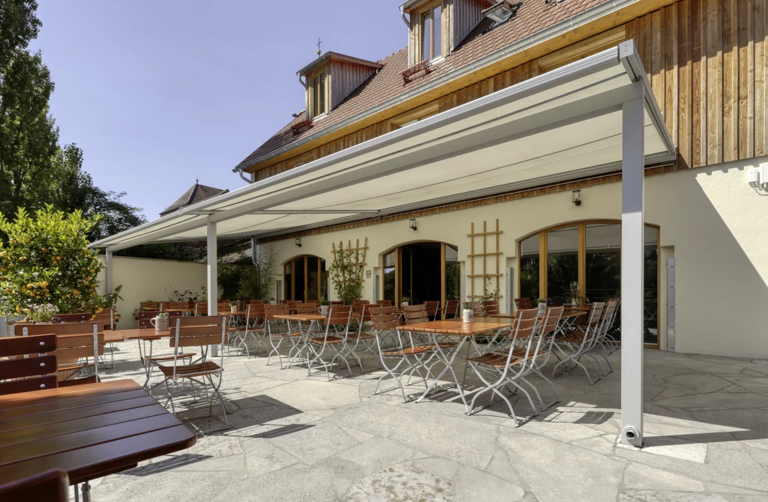 Außenansicht eines gemütlichen Biergartens mit Sonnenschirm und Holzmöbeln